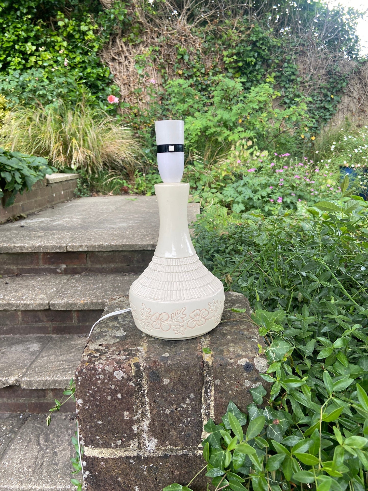 a white cream retro pottery lamp; beautiful bottle shape, glazed but with carved moulded detail; bottom of which is flowers. typical 1970s style. working with original wiring