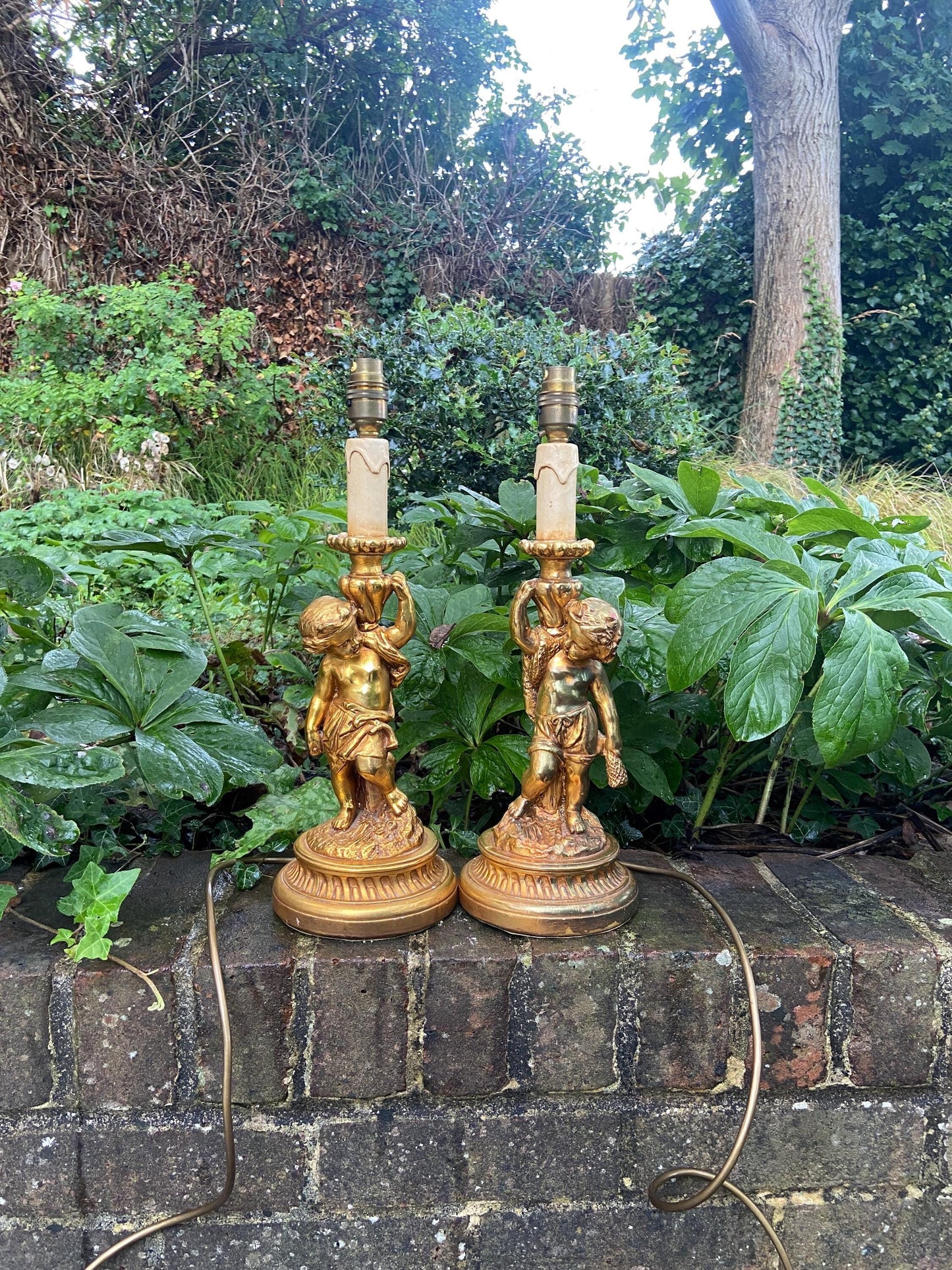retro vintage cherub table lamps; working. resin or plaster. painted in gilt. whilst a pair they are different figurines. in fantastic vintage condition. excellent lamps for a bedroom, hallway entryway or living room.