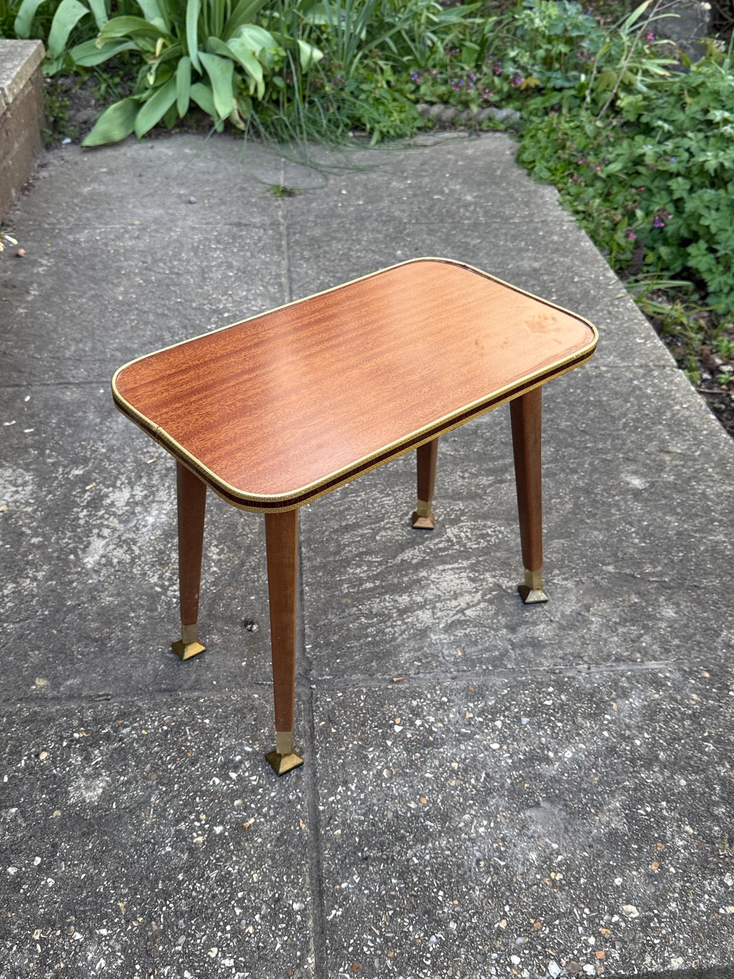 Mid-century modern small table with laminated woodgrain top, tapered legs and metal swivel capped feet