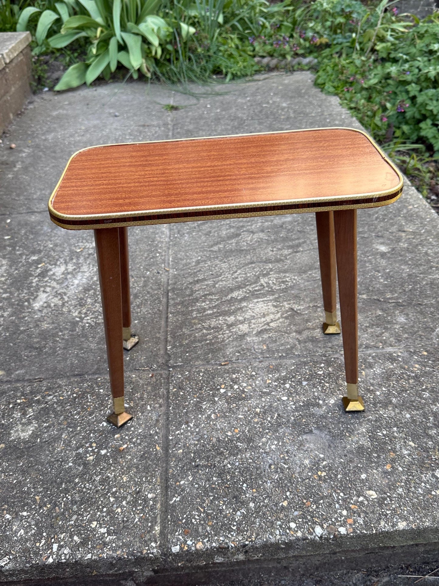 Mid-century modern small table with laminated woodgrain top, tapered legs and metal swivel capped feet