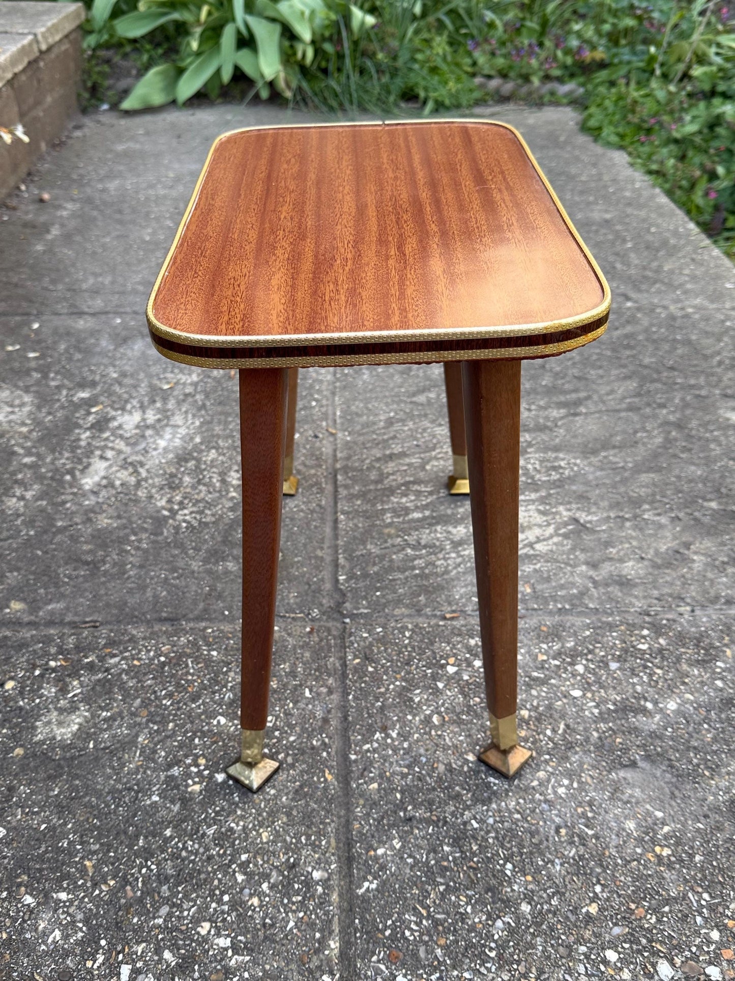 Mid-century modern small table with laminated woodgrain top, tapered legs and metal swivel capped feet