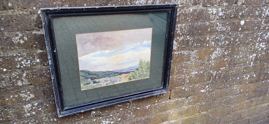 delightful antique watercolour painting of houses in a valley. Lovely landscape, slight naivety in the painting. Framed in a wonderful early 1900 wooden frame with cracked and shabbied black moulded gesso. Glazed frame and dark green mount.