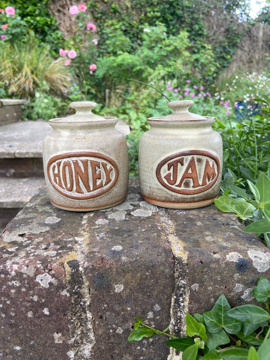 retro pottery stoneware storage jars, one for honey, one for jam. Lovely browns and creams. Labelled honey and labelled jam. Small lids with holes for spoons. very sweet littlejars. great condition.