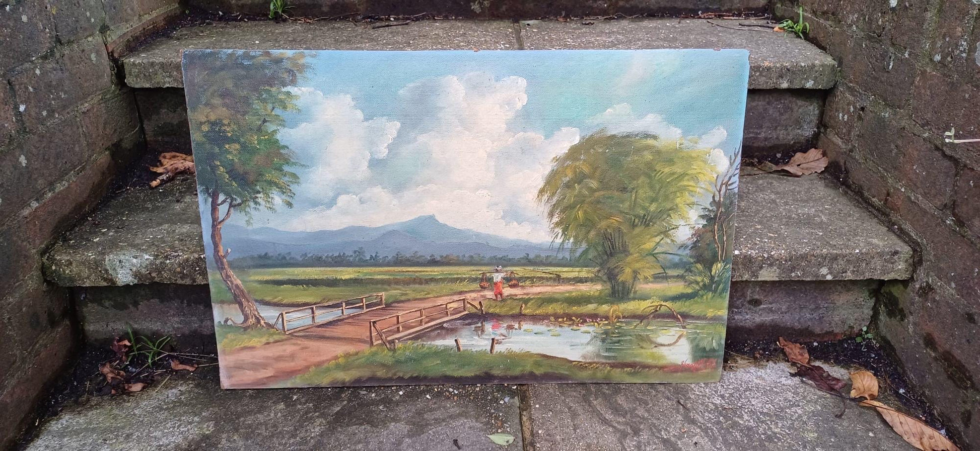 1960s oil on board by artist Yusoff Abdullah. Rural scene of a villager / farmer carrying goods across a field. Signed painting