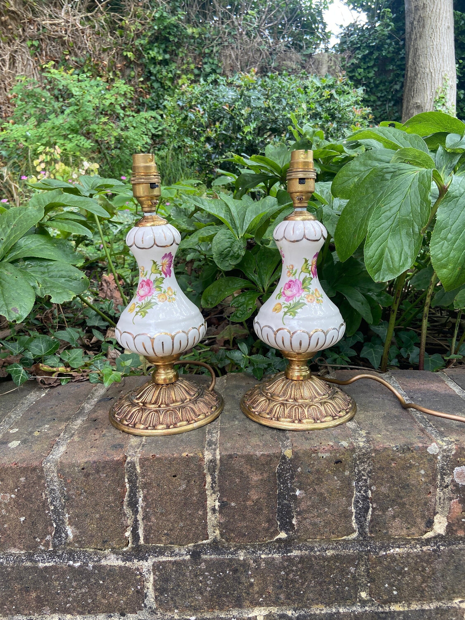 1970s pair of porcelain and metal table lamps. Lovely white porcelain with painted flowers and some gilt details. Very attractive. needs wiring attached and plugs.