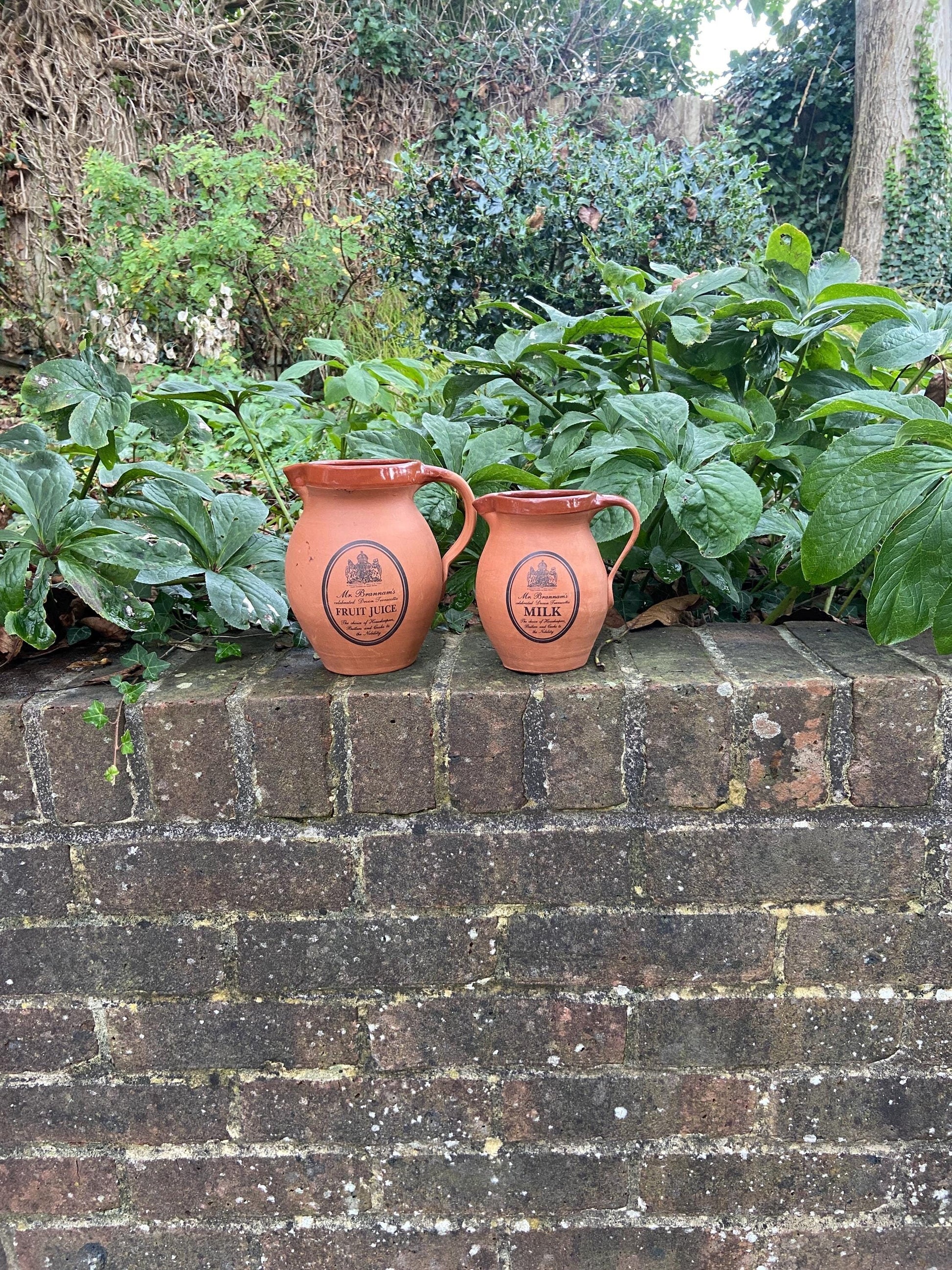 two terracotta jugs perfect for breakfast. made out of pottery by Devon Pottery. Branded Mrs Brannams. One for juice and one for milk. vgc