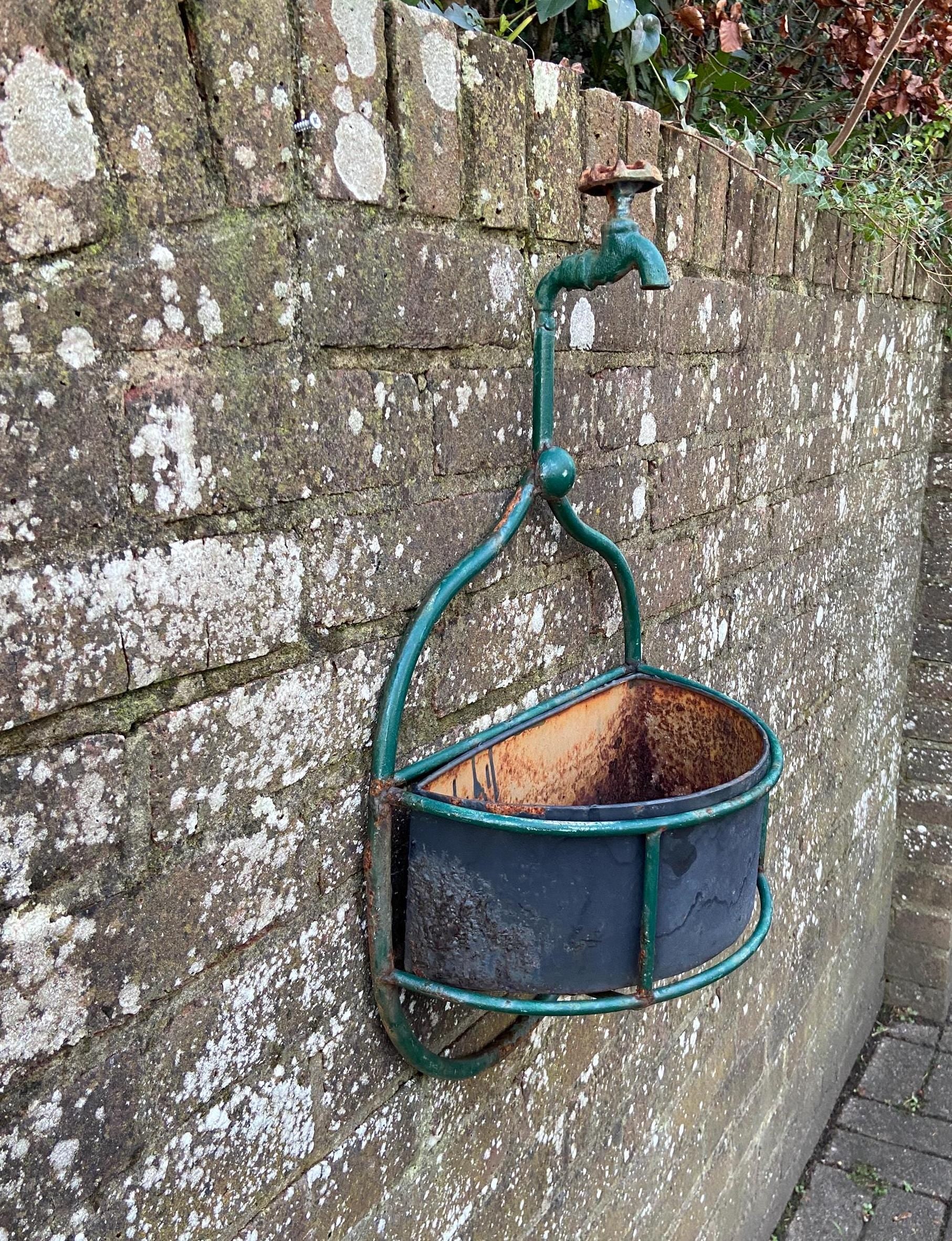 unique outdoor planter made out of fire hose tap and green metal frame. original metal basket. wall basket
