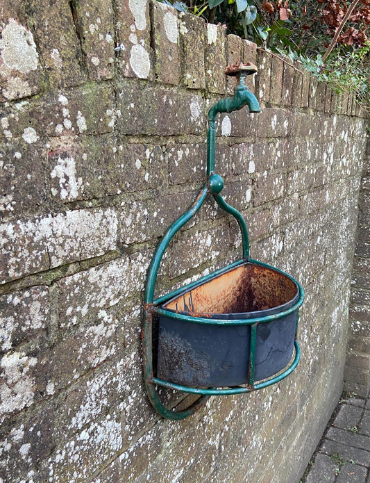 unique outdoor planter made out of fire hose tap and green metal frame. original metal basket. wall basket
