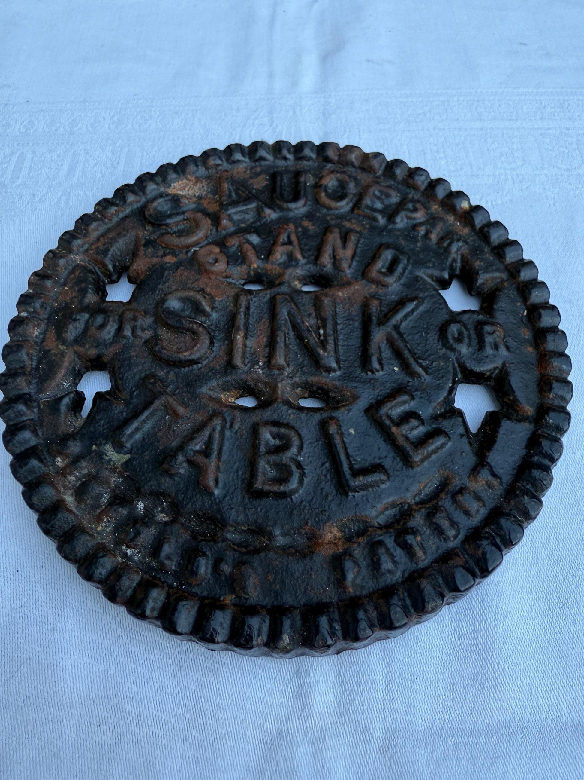 Fantastic heavy iron tivert or pot stand with wording "Saucepan stand for sink or table" - great for kitchens and tables 17cm wide