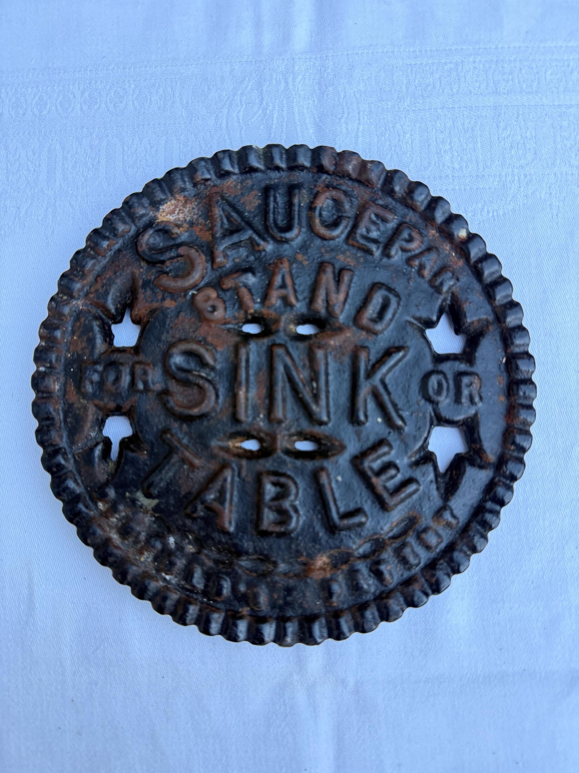 Fantastic heavy iron tivert or pot stand with wording "Saucepan stand for sink or table" - great for kitchens and tables 17cm wide