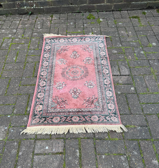 dusky pink rose rug. with black and cream floral detail. A light rug, likely wool. good condition