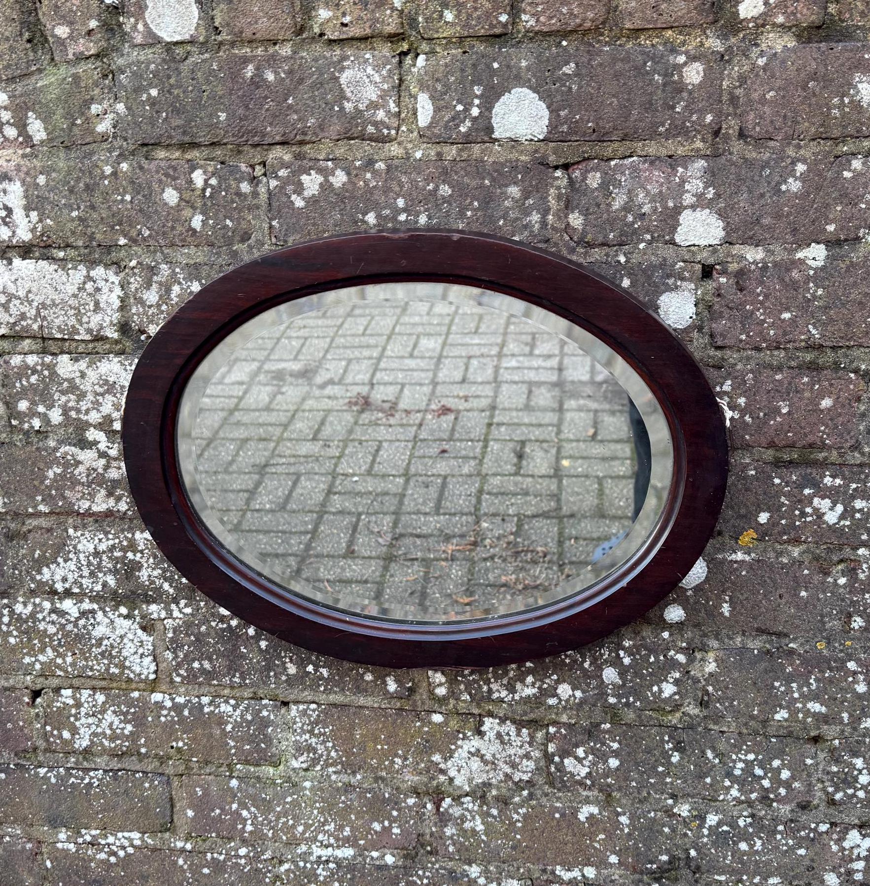 lovely vintage wooden mirror with bevelled glass, in a oval wooden frame.  likely antique.