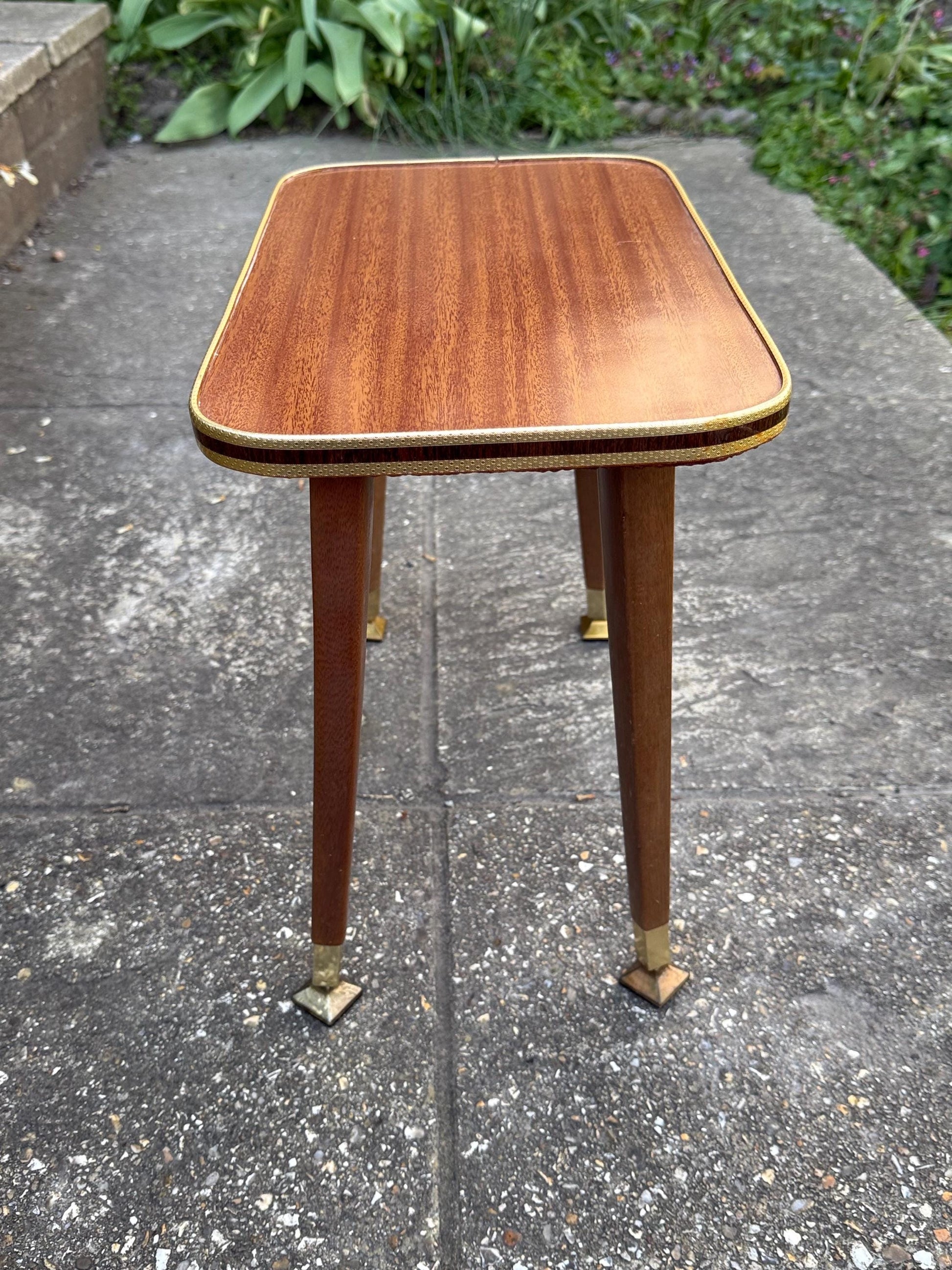 Mid-century modern small table with laminated woodgrain top, tapered legs and metal swivel capped feet