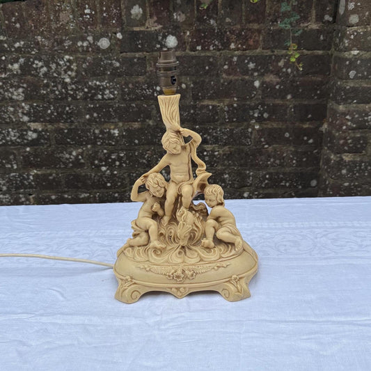 resin table lamp in a cream colour with loads of patina and markings. three cherubs posing on the lamp. working and pat tested