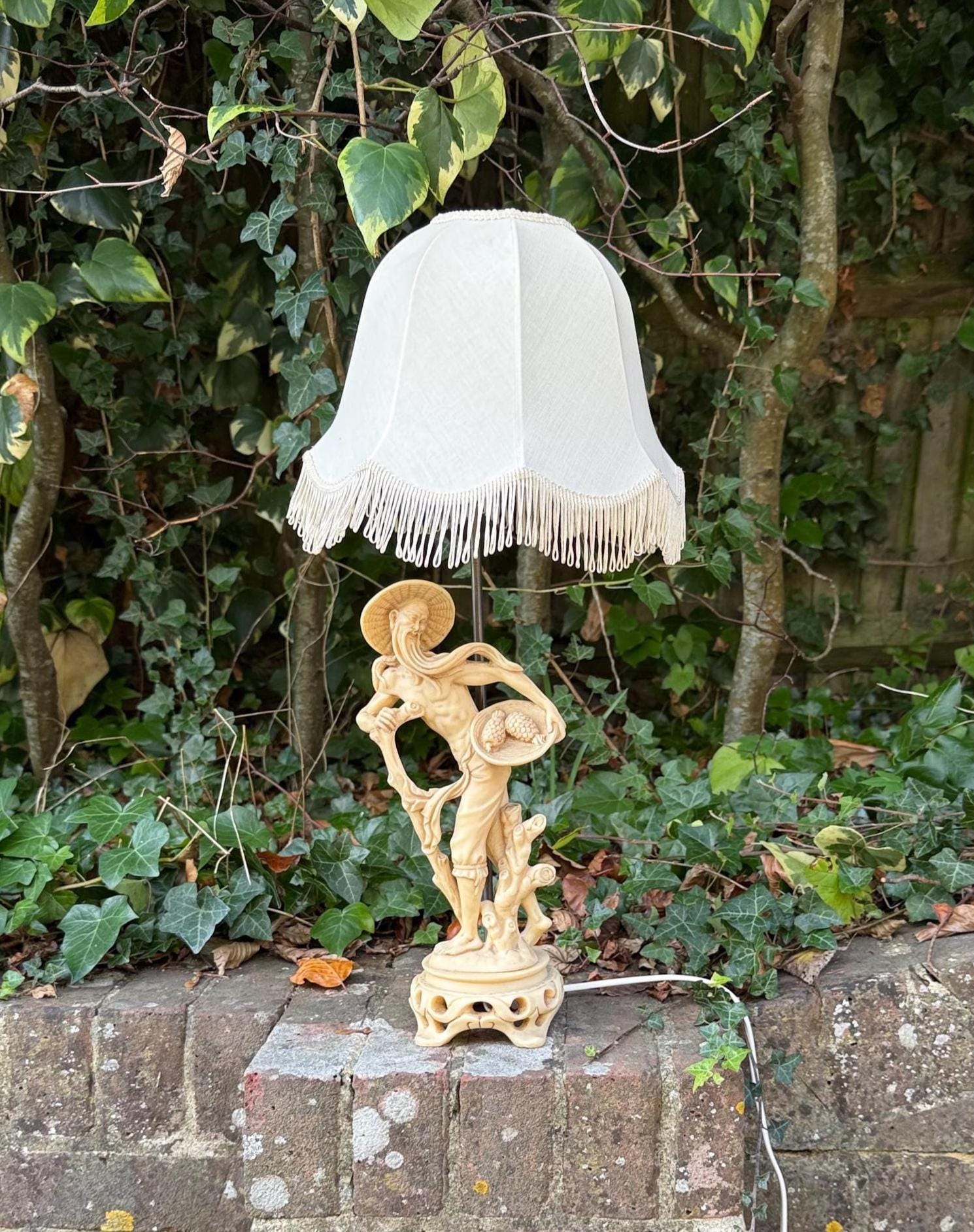 original 1960s retro resin lamp with oriental man figurine and original retro linen shade, fringed. Bell shaped shade. yellow patina rich lamp